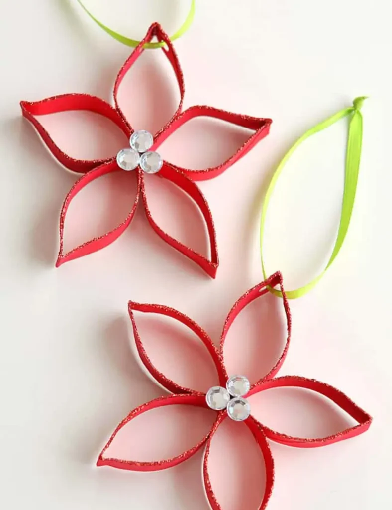 Two red glittered poinsettia ornaments made from a paper roll, with a rhinestone center and green ribbon.
