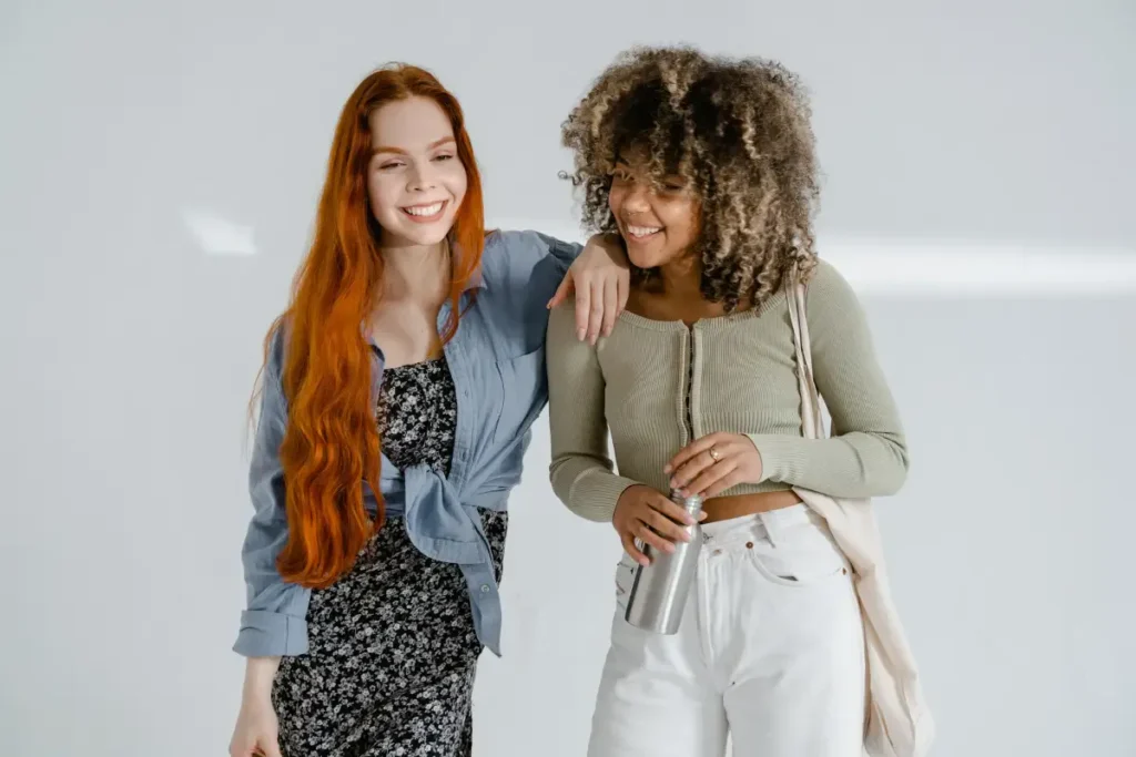 Two women smiling and enjoying each other's company in a bright indoor setting.. self-care ideas for women
