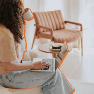 Woman working on a laptop with a coffee, planning her Etsy shop name.