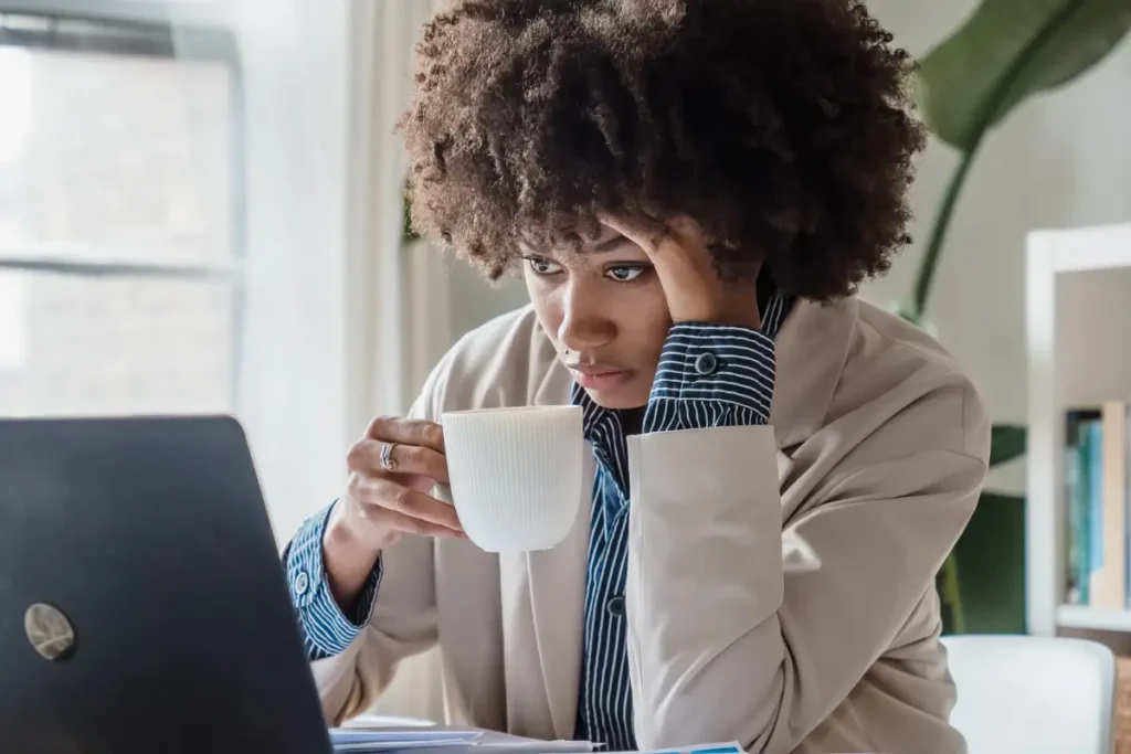 Woman working at desk with laptop and coffee cup, focusing on tasks. self-care ideas for women 