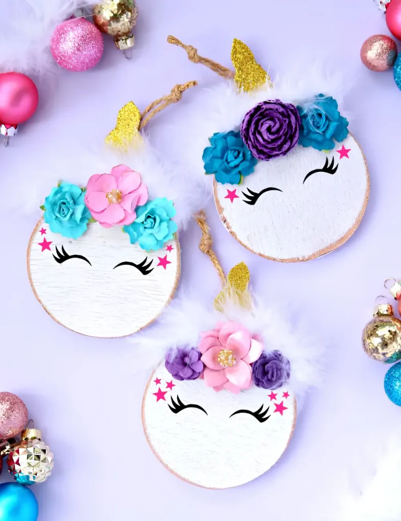 Wood slice unicorn ornament with a feather boa mane, gold glitter horn, paper flowers and vinyl eyes.