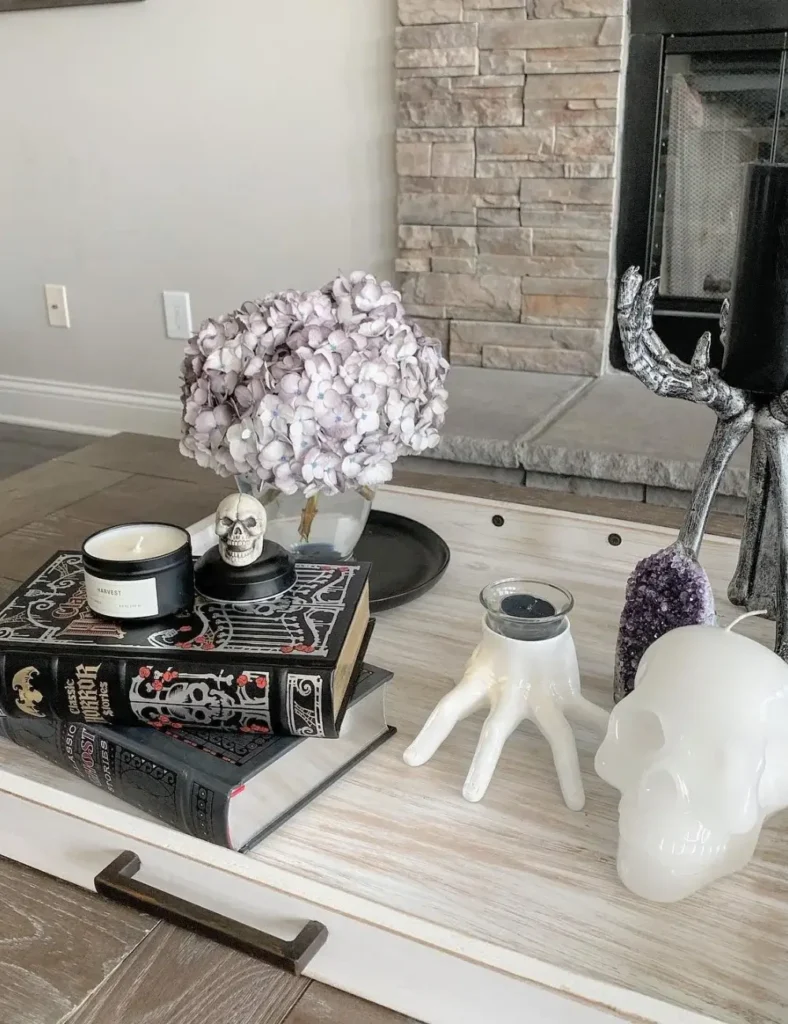 Coffee table tray styled with gothic horror books, a skull candle topper, dried hydrangeas and a white witch's hand candle holder