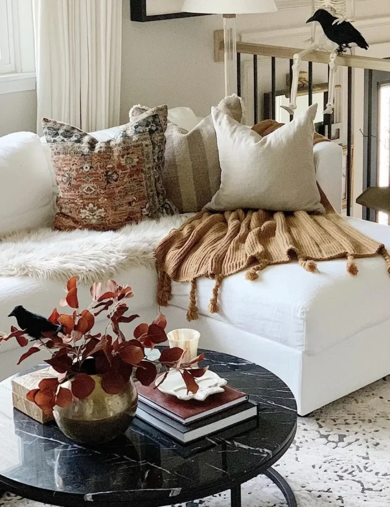 Black marble coffee table with a brass vase of red foliage, a perched black crow figurine and a stack of books