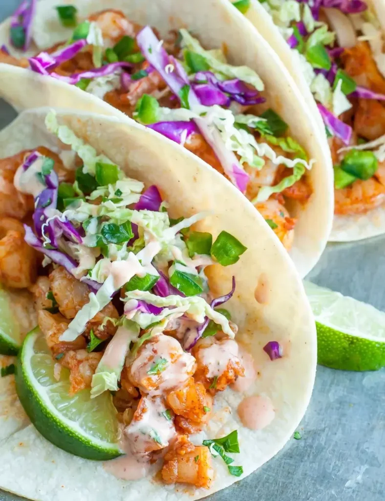 Sriracha shrimp tacos topped with cilantro lime slaw on corn tortillas