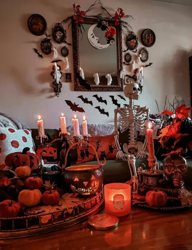 Halloween coffee table styled with a mini skeleton, jack-o-lantern cauldron, dripping candelabra and orange pumpkins on a bamboo tray