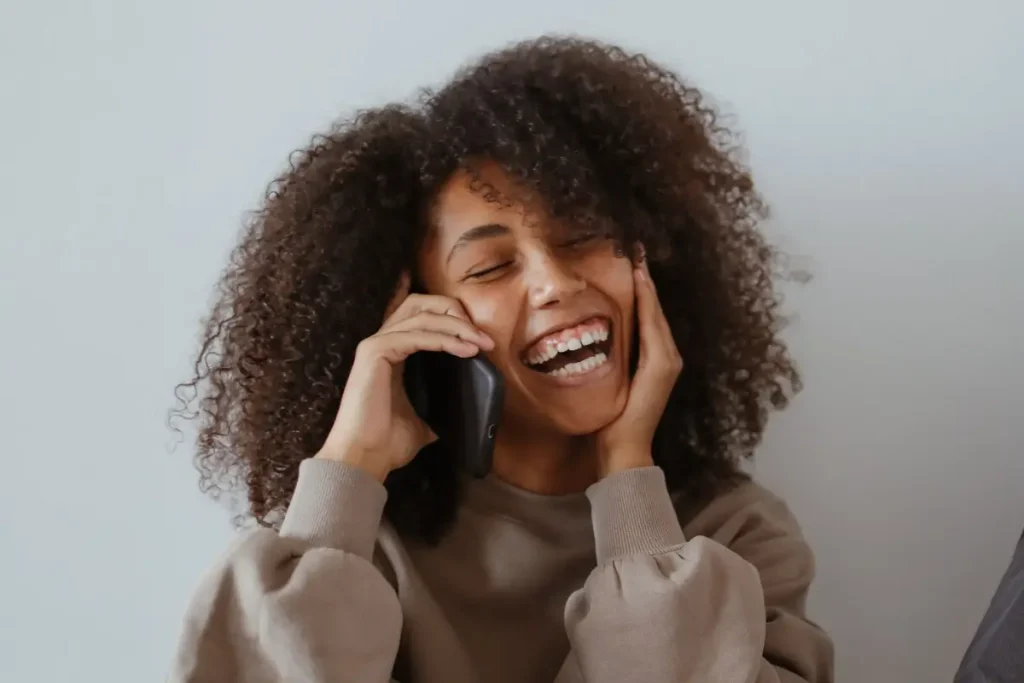 A joyful young woman happily talking on her smartphone indoors.