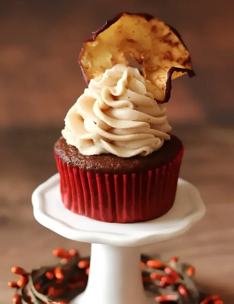 An Apple butter cupcake topped with a piped buttercream rose and apple chip