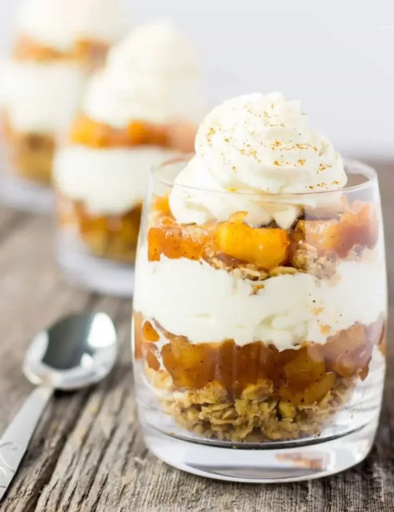 Apple pie parfaits layered in glasses with crumb topping and whipped cream