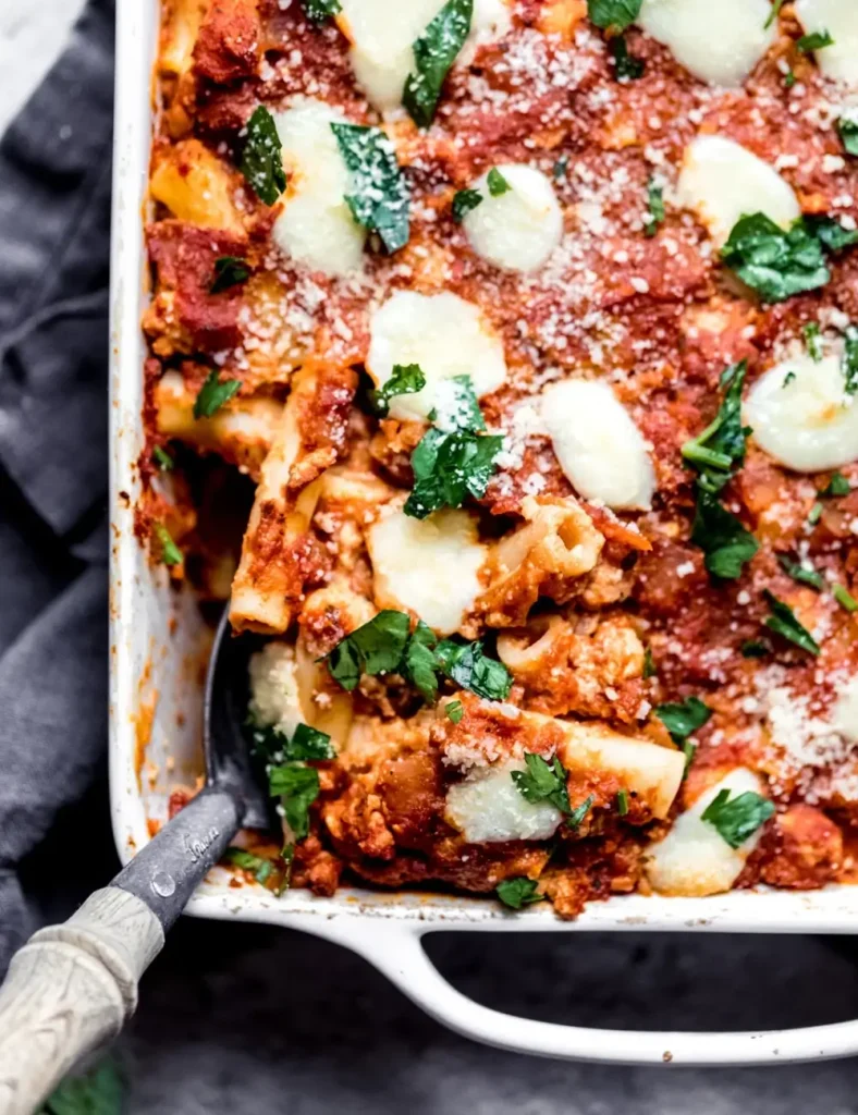 Baked pumpkin pasta in a dish with bubbling melted mozzarella and fresh parsley