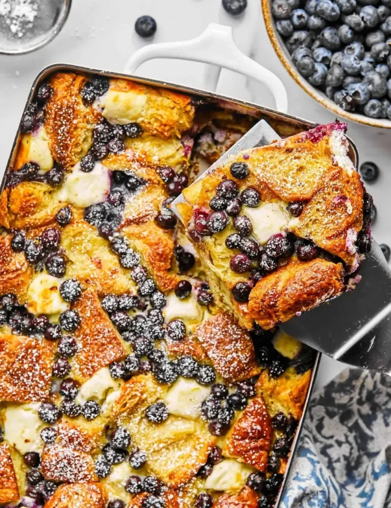 Blueberry cream cheese croissant casserole in a baking dish with blueberry sauce poured over the top