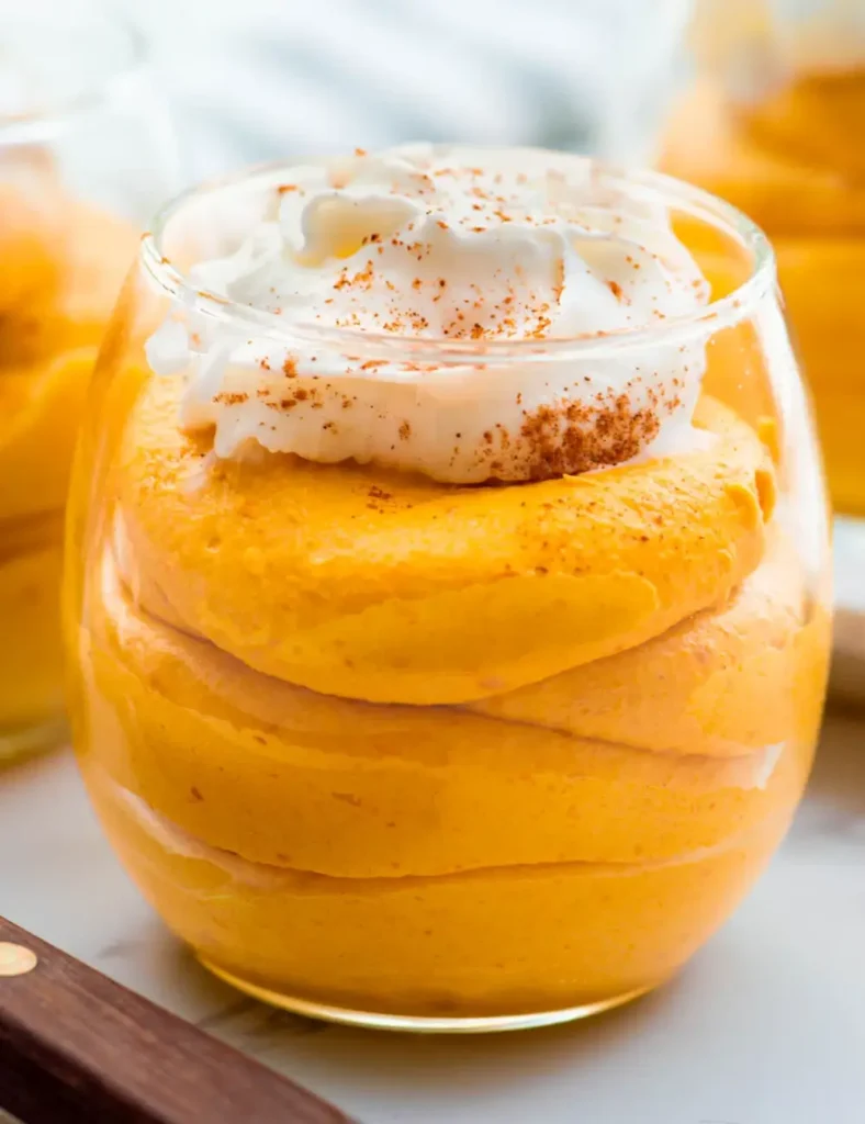 Bowl of pumpkin fluff topped with whipped cream and a sprinkle of cinnamon