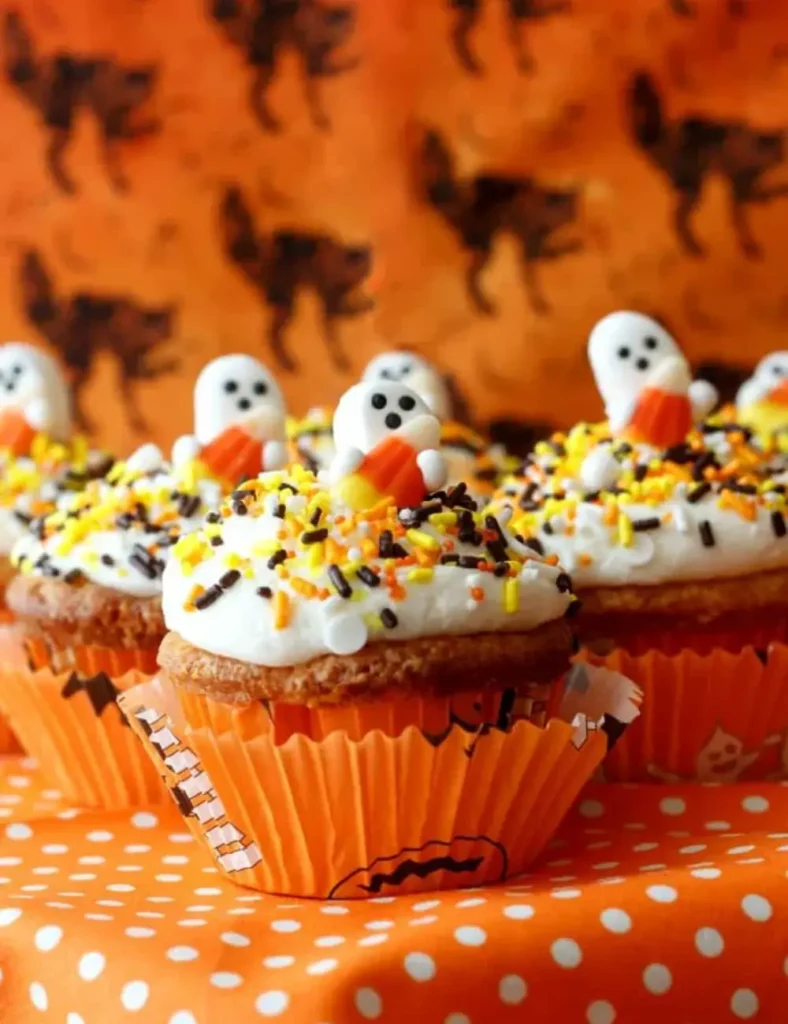 Candy corn cupcake decorated with orange, yellow and white frosting and a candy corn ghost topper