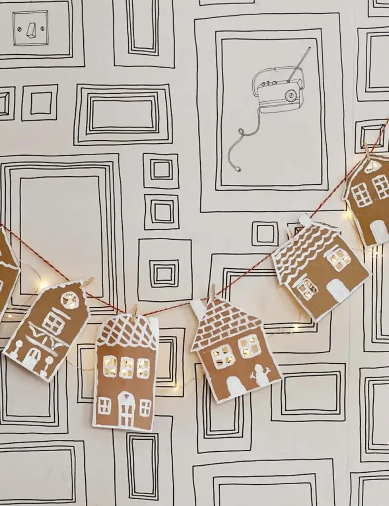 Cardboard gingerbread house garland lit up with copper string lights