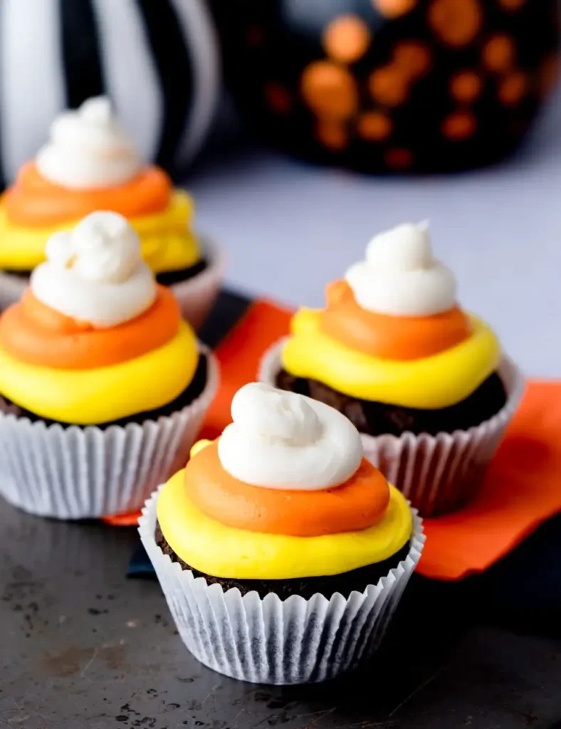 Chocolate cupcake topped with yellow, orange and white frosting in a candy corn design
