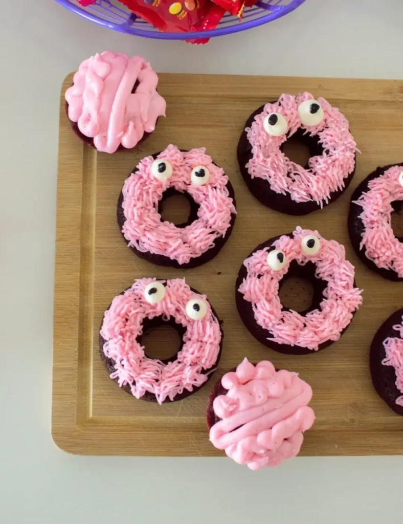 Chocolate donuts decorated with pink buttercream fur and monster eyes