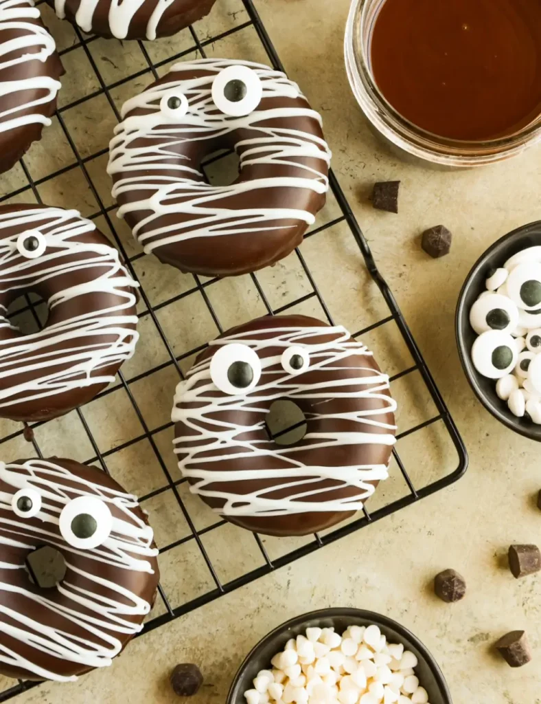 Chocolate mummy donuts drizzled with white chocolate bandages and candy eyes