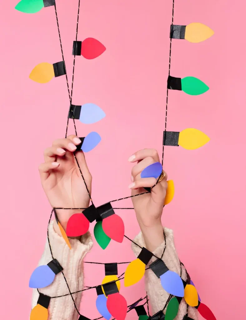 Colorful paper light bulb cutouts attached to balloons as festive garland