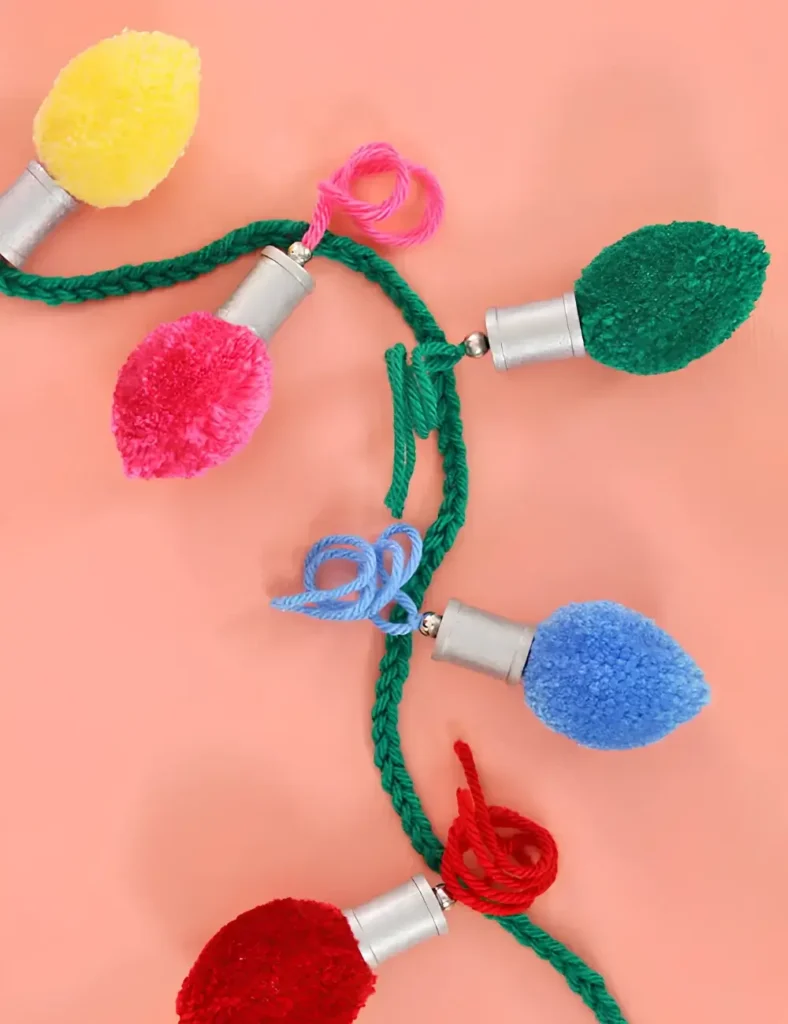 Colorful pom poms shaped like retro Christmas lights with silver wooden bases