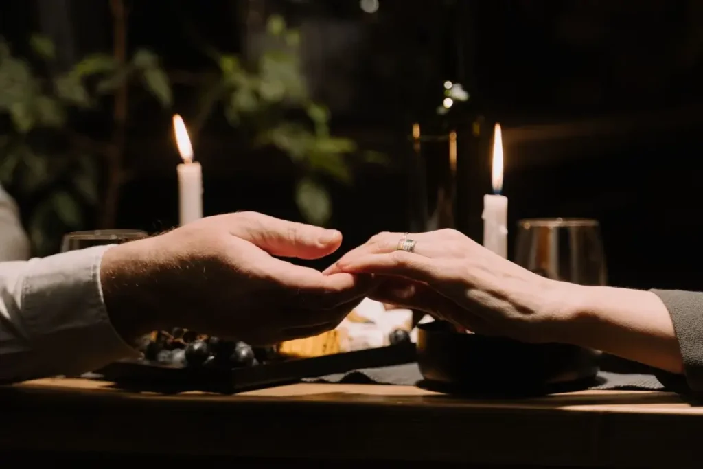 Couple holding hands at a romantic candlelit dinner, creating an intimate atmosphere