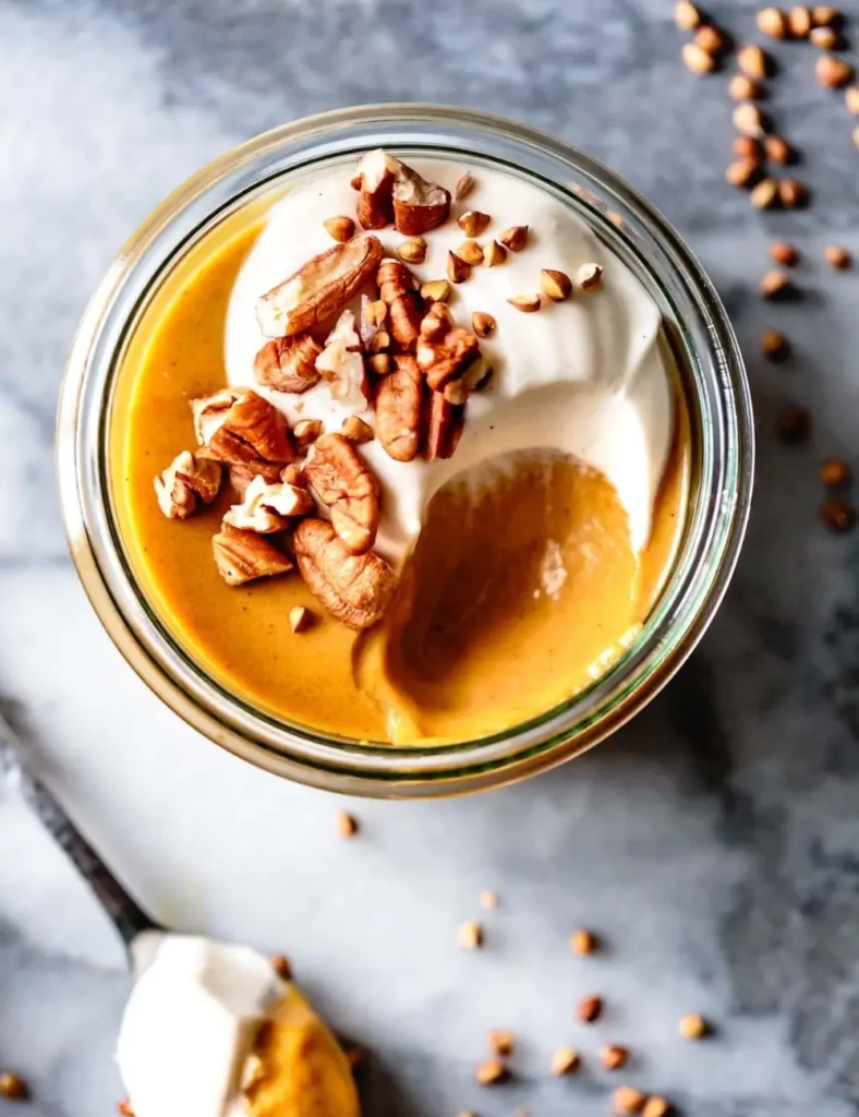 Creamy pumpkin pudding in a glass jar topped with whipped mascarpone