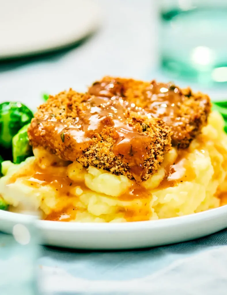 Crispy panko-crusted holiday tofu slices served over mashed potatoes with gravy and thyme