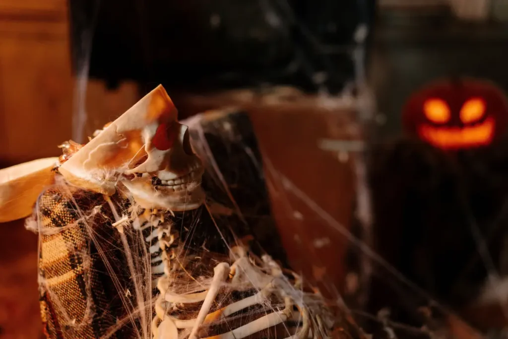 Eerie close-up of a skeleton wrapped in cobwebs with a glowing pumpkin