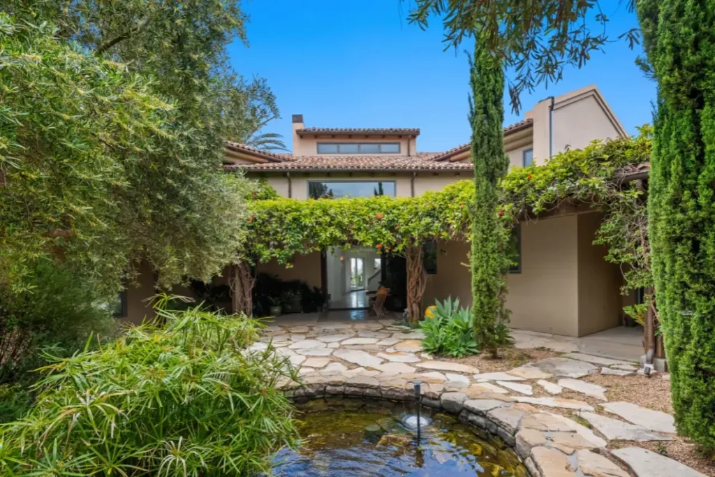 Elegant Mediterranean villa surrounded by verdant gardens and tranquil pond