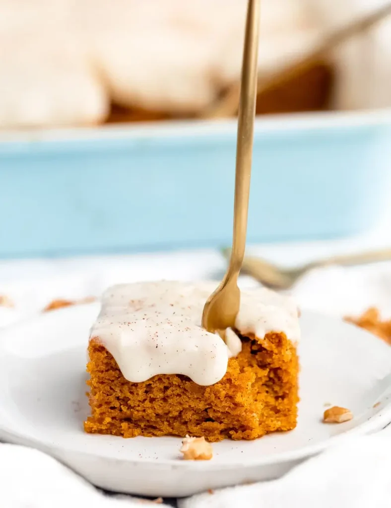 Frosted pumpkin sheet cake sliced on a plate with a fork