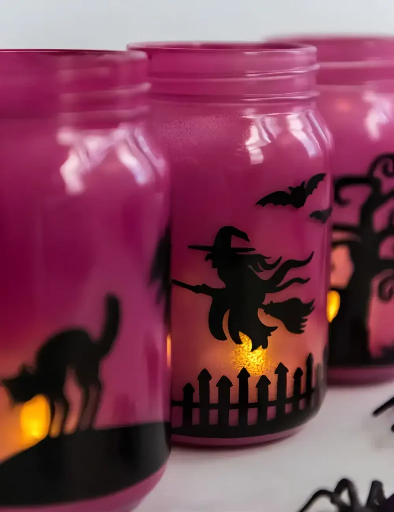 Frosted purple glass mason jar luminaries with black vinyl spooky silhouette designs, lit from inside