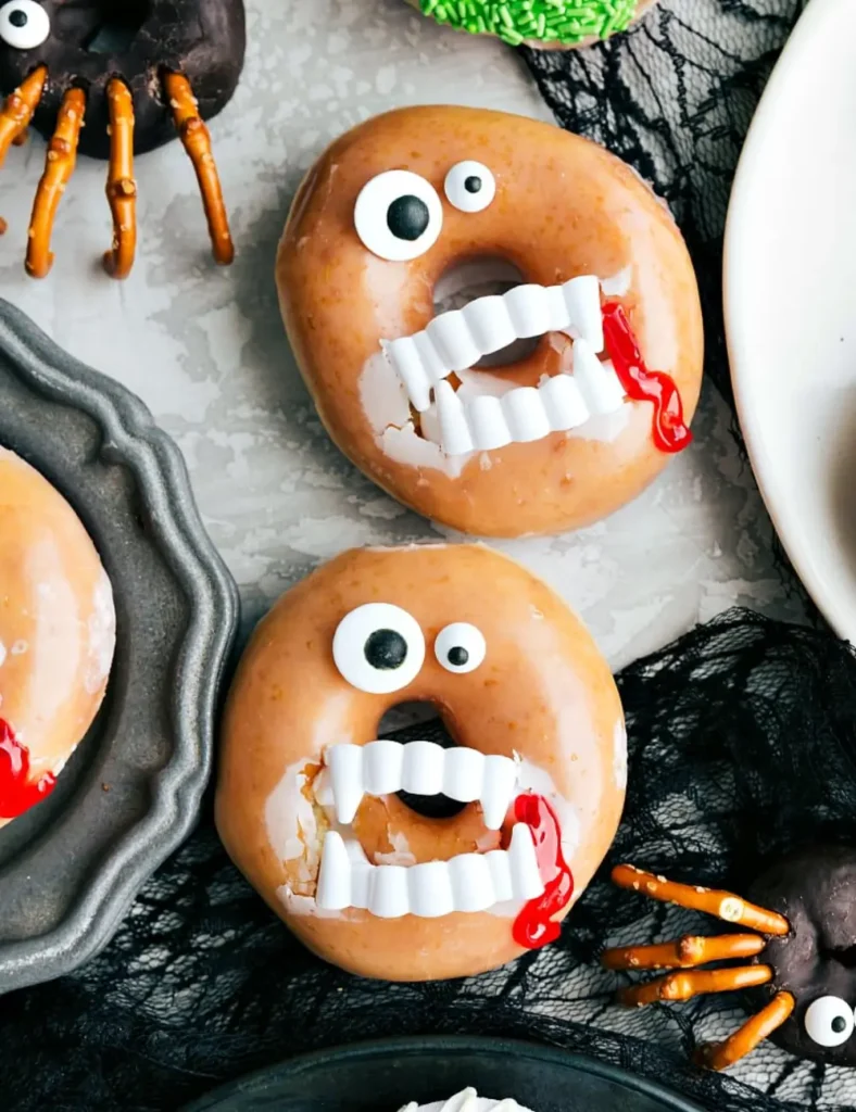 Glazed donut decorated with plastic vampire fangs, red edible gel, and candy eyes
