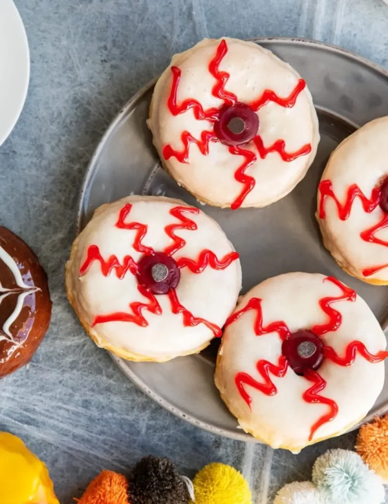 Glazed donut decorated with red gel bloodshot lines and a gummy candy eyeball center