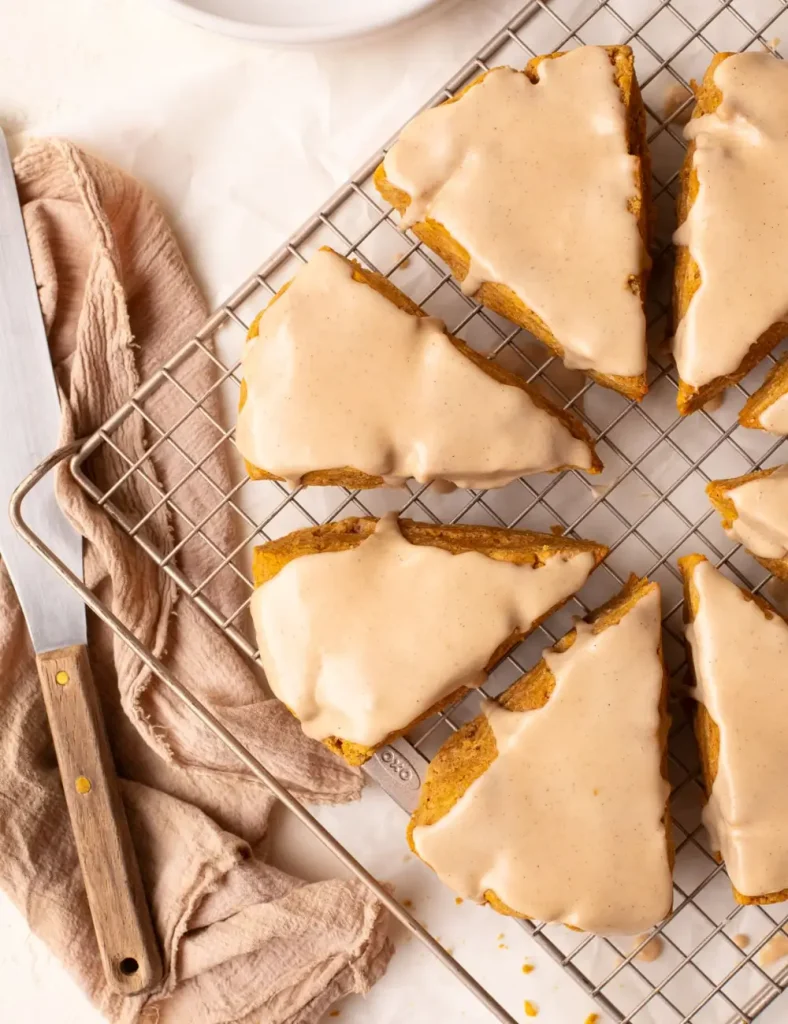 Gluten-free pumpkin scones drizzled with maple glaze on a wire rack