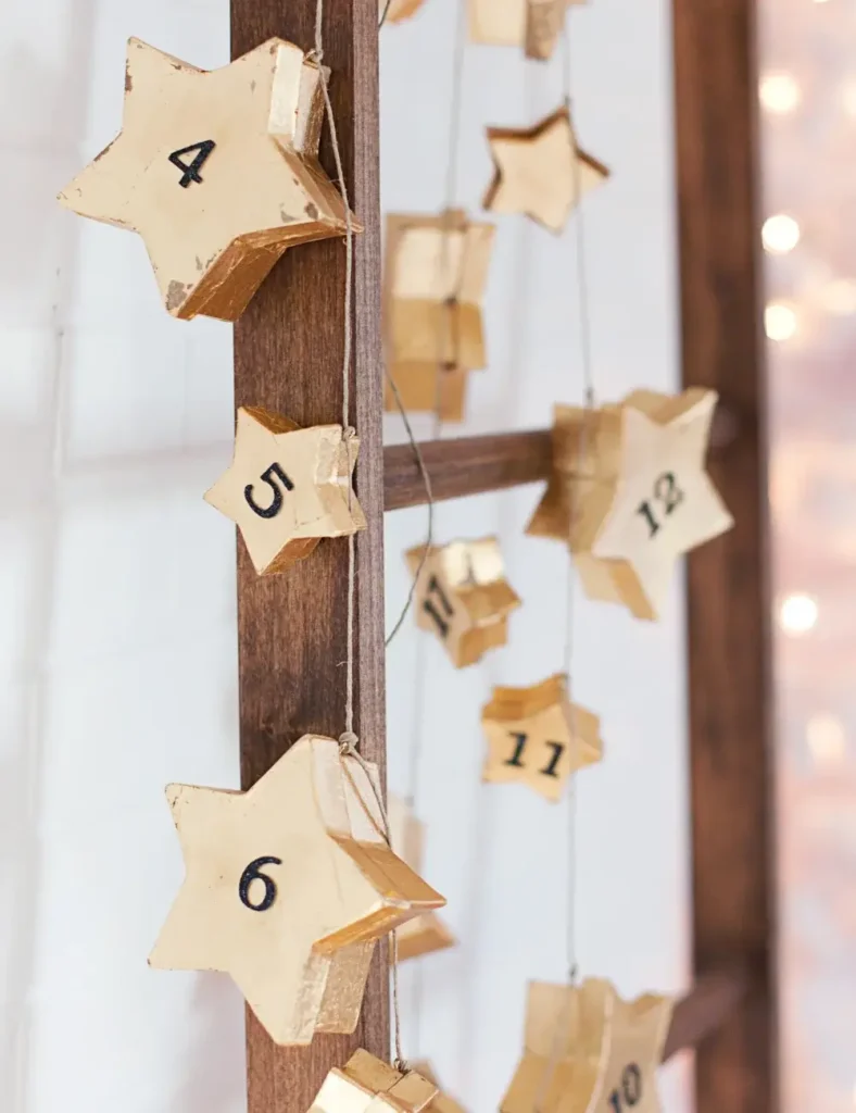 Gold star advent calendar garland with numbered boxes hanging on a ladder