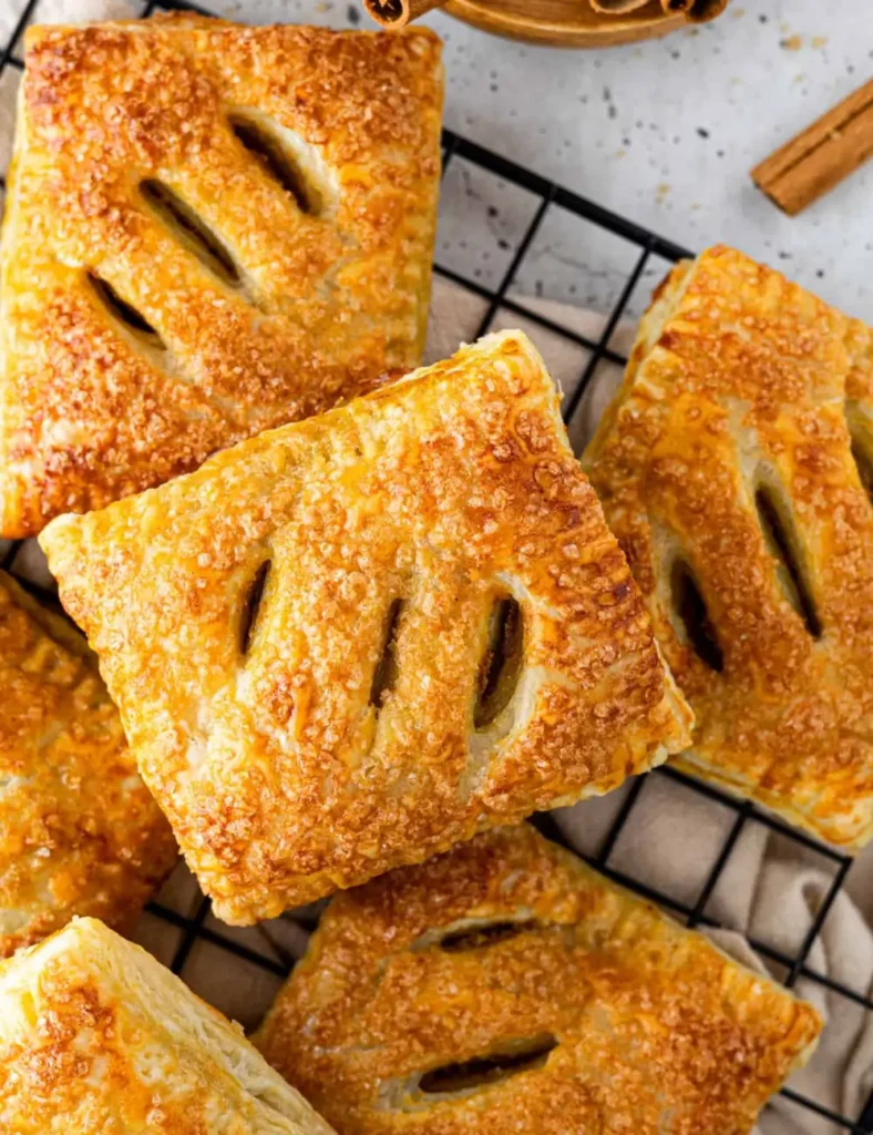 Golden pumpkin hand pies made with puff pastry cooling on a wire rack