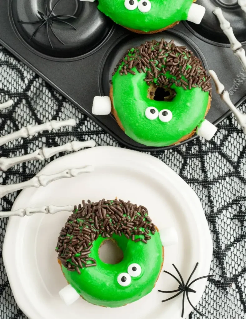 Green Frankenstein-decorated donuts with candy eyes, chocolate sprinkles, and marshmallow neck bolts