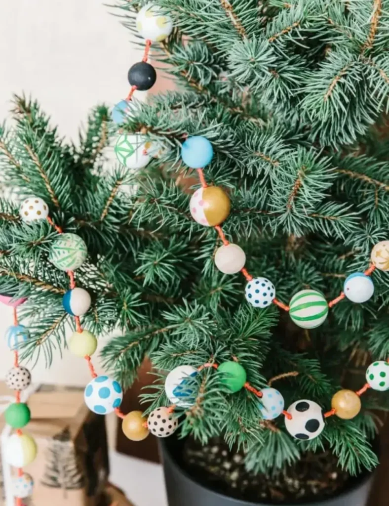 Hand-painted wood bead garland in bright colors and patterns draped on a Christmas tree