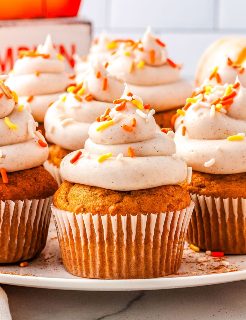 Large batch of pumpkin cupcakes topped with cinnamon cream cheese frosting