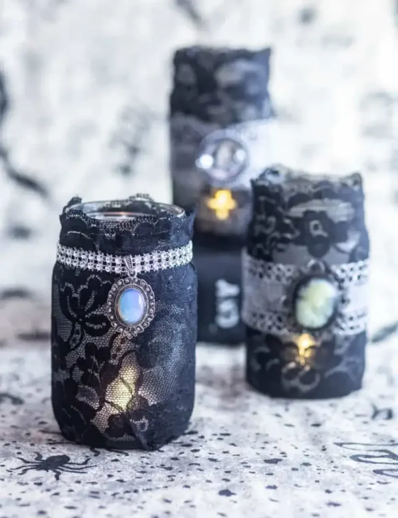 Mason jar candle holder wrapped in black lace with a decorative pendant, used as gothic Halloween decor