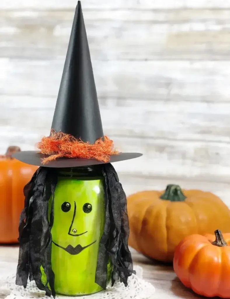 Mason jar witch lantern with green tinted glass, a cardstock witch hat and yarn hair