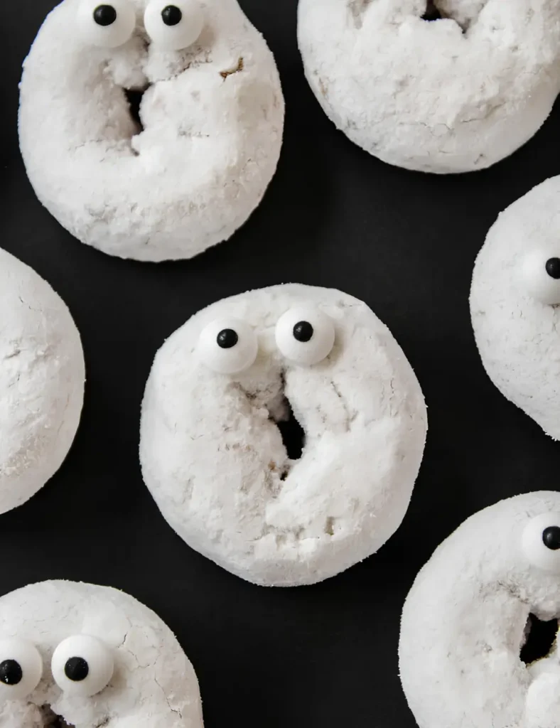 Mini powdered sugar donuts decorated with candy eyes to look like ghosts