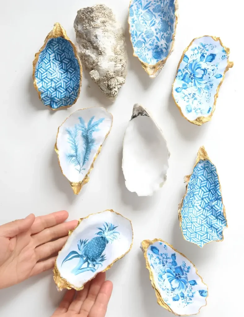 Oyster shell dish decoupaged with a blue and white floral pattern and gold painted edge