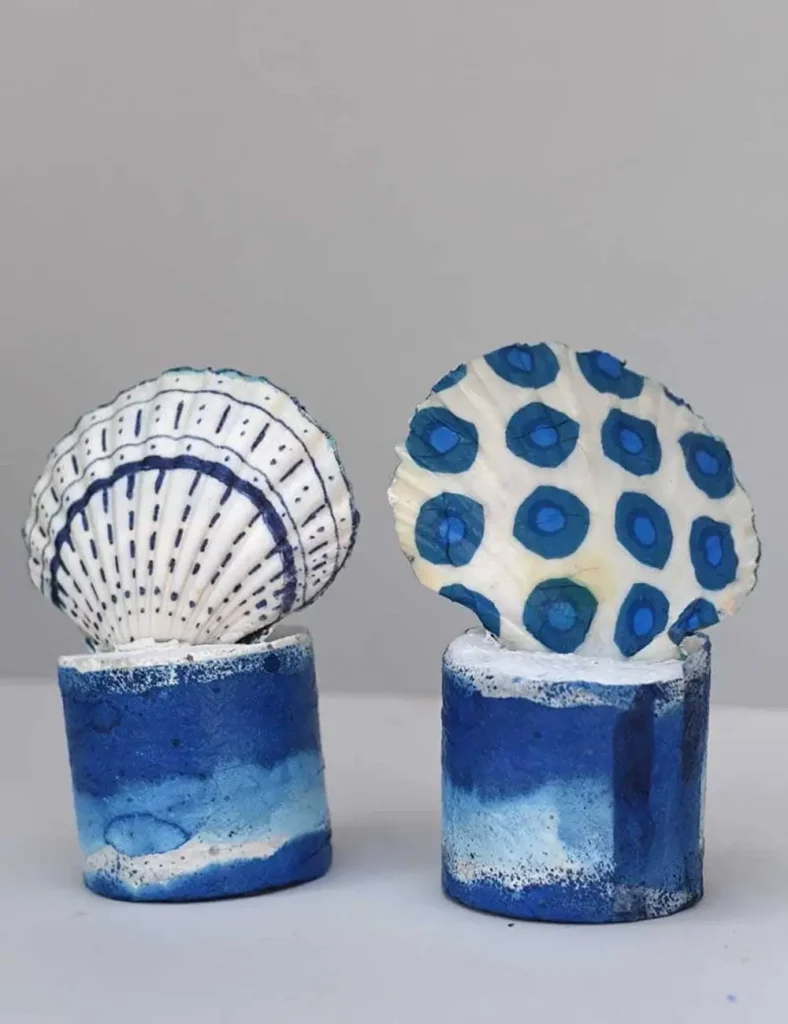 Pair of scallop shell bookends set in white concrete bases on a shelf with books
