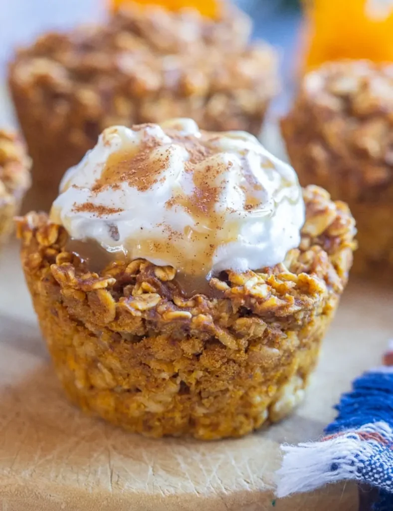Pumpkin pie baked oatmeal cups topped with whipped cream and caramel sauce