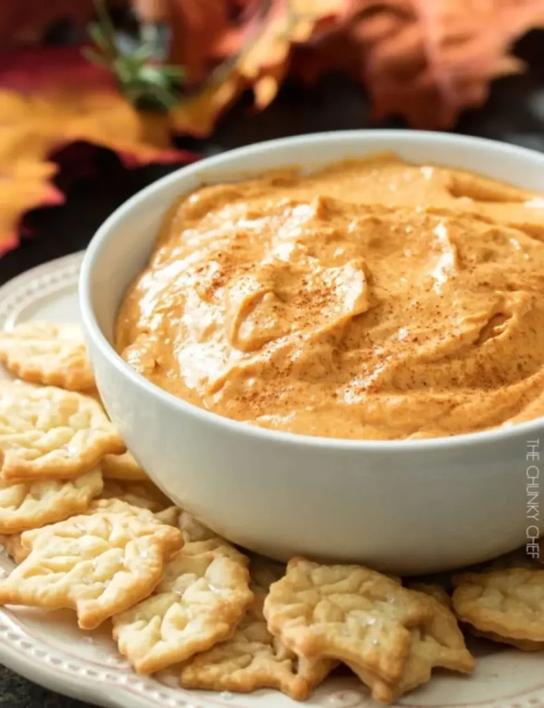 Pumpkin pie dip in a bowl served with gingersnaps and apple slices