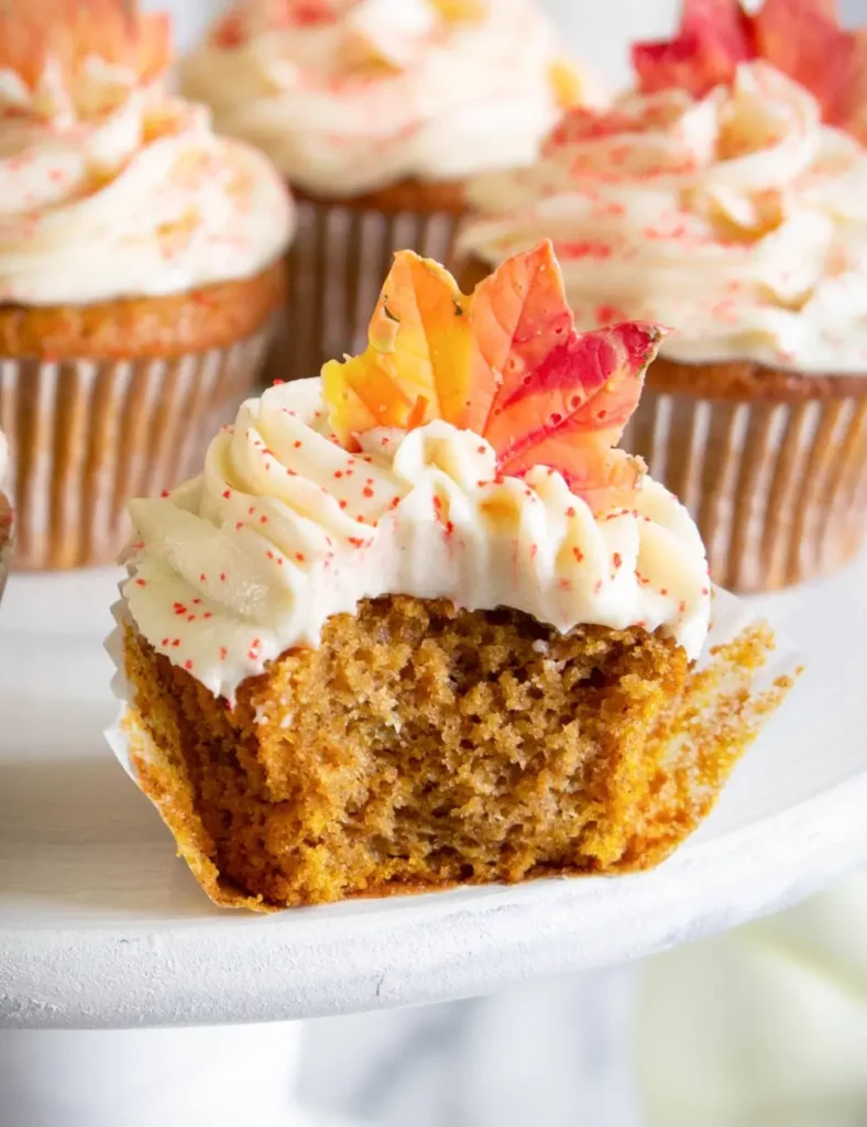 Pumpkin spice cupcakes with cream cheese frosting topped with candy fall leaves