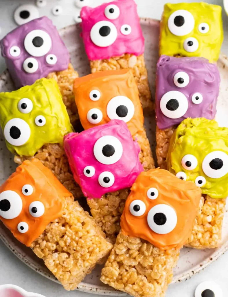 Rice Krispie treats dipped in colorful orange, green, and purple candy melts topped with candy eyes