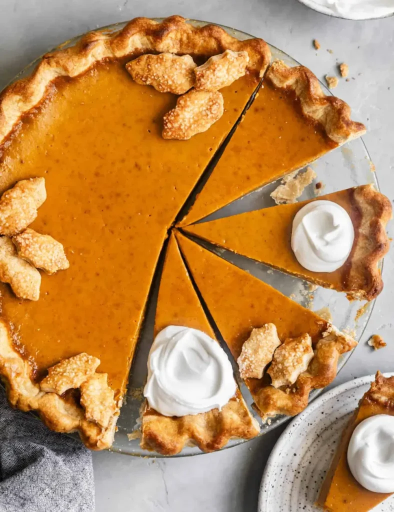 Slice of gluten-free dairy-free pumpkin pie topped with coconut whipped cream