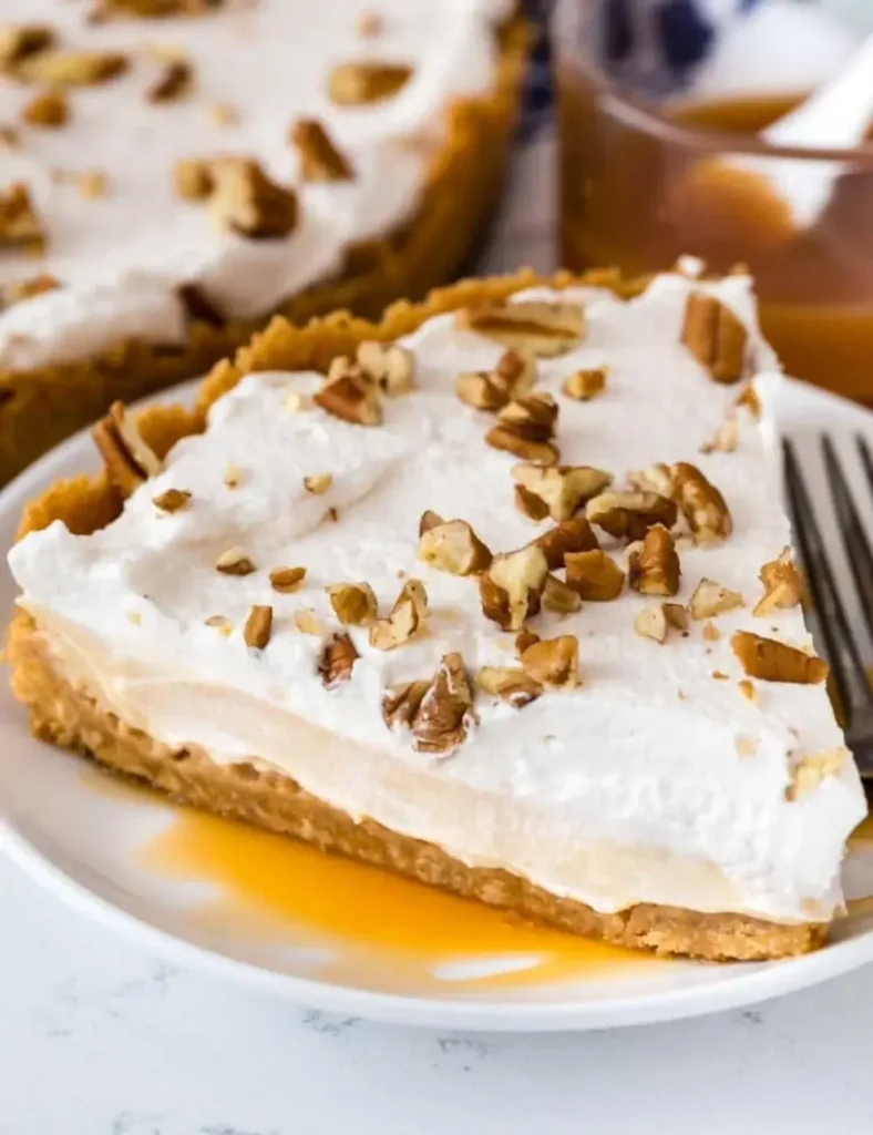 Slice of no-bake butterscotch pudding pie topped with whipped cream and pecans