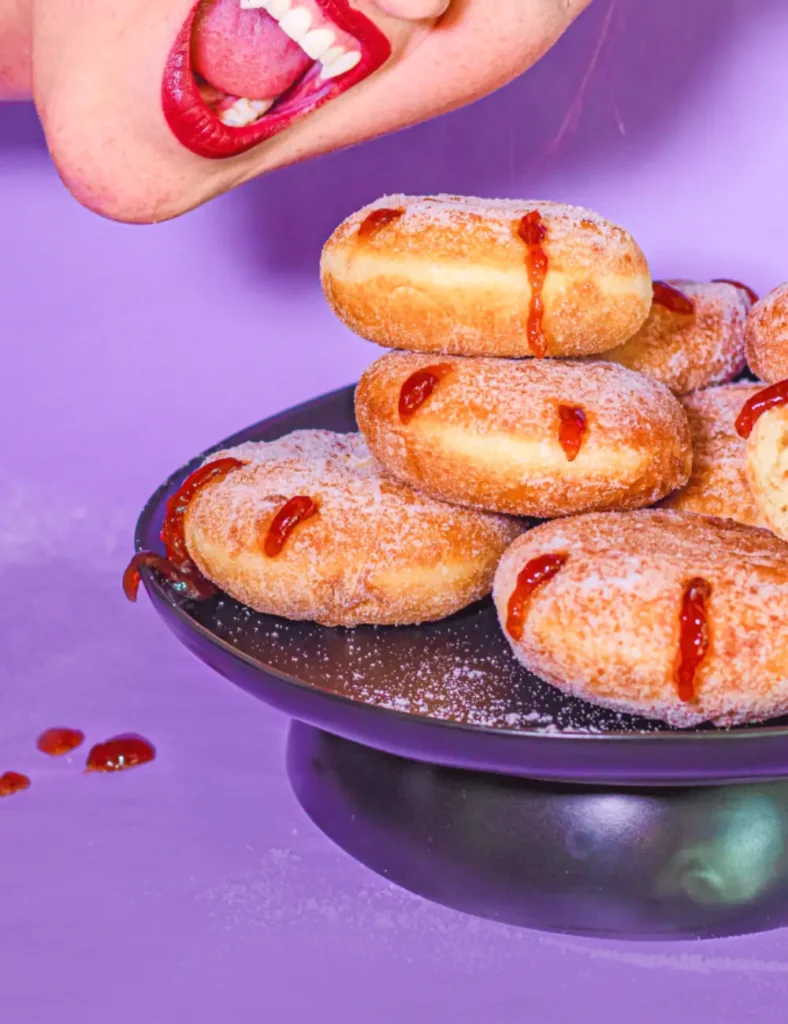 Sugar-dusted brioche donuts with red jam dripping from vampire bite-style holes