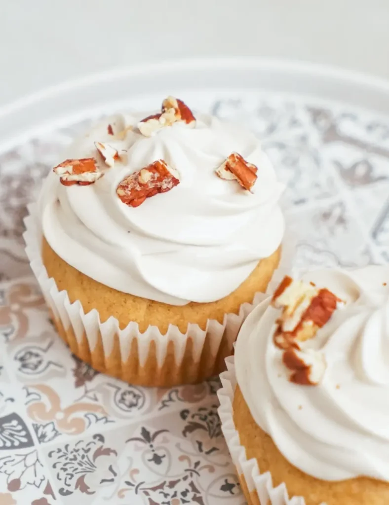Sweet potato cupcakes topped with fluffy marshmallow frosting and chopped pecans
